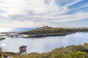 Coastal community with waterfront homes positioned along a scenic inlet with observation deck and natural vegetation.