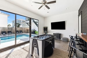 Your entertainment hub opens to a sparkling pool, with foosball, bigscreen TV, and bar seating for endless fun.