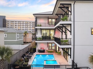 Modern threestory vacation rental showcasing multiple balconies, private swimming pool, and contemporary architecture in a coastal neighborhood setting.