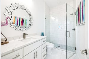 Unwind in your stunning bathroom featuring marble countertops, a glassenclosed shower, and vibrant artwork that adds personality to your private retreat.