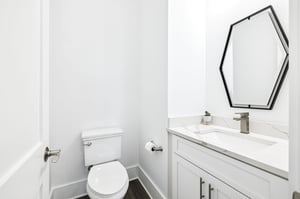 Your elegant powder room features marble countertops, modern fixtures, and a striking geometric mirror for your convenience.