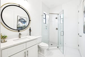Refresh in your pristine white bathroom featuring a sleek glass shower, elegant round mirror, and marble countertops—your perfect morning retreat.