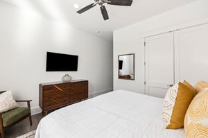 Unwind in your serene bedroom featuring crisp linens, warm wood accents, and a ceiling fan for perfect comfort.