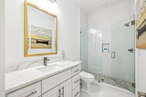 Pamper yourself in this pristine marble bathroom with elegant gold accents and a spacious glass shower.
