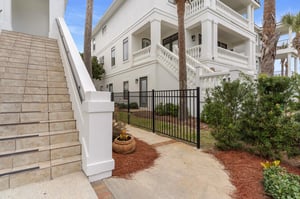 Elegant property entrance featuring classic white architecture with ornate balustrades and tropical landscaping.