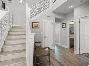 Step into your elegant entryway featuring rich hardwood floors, sophisticated gray walls, and a welcoming wooden bench where you can pause and settle in.