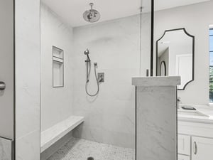 Step into your luxurious walkin shower featuring elegant marble walls, rainfall showerhead, and builtin bench for pure relaxation.