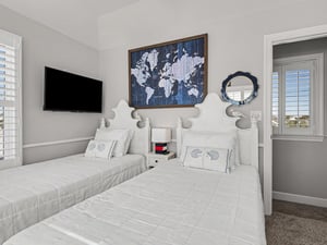 Drift off to sleep surrounded by nautical charm—twin beds with crisp linens, world map art, and gentle natural light create your perfect coastal retreat.