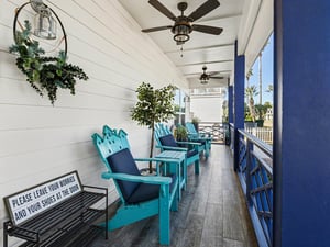 Unwind on your covered porch with turquoise chairs and coastal breezes, where ceiling fans keep you cool while palm trees sway nearby.
