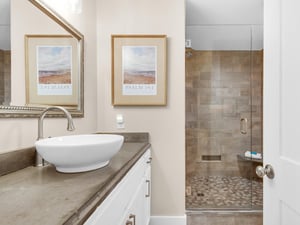 Unwind in your spalike bathroom with elegant vessel sink and luxurious walkin shower featuring beautiful stone tilework.