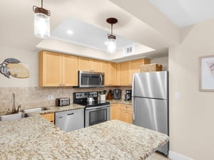 Your fully equipped kitchen features granite countertops, stainless steel appliances, and warm wood cabinetry—perfect for preparing meals together.