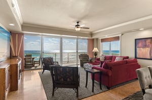 Unwind in your oceanfront sanctuary with panoramic sea views, plush red sofas, and direct balcony access to endless azure horizons.