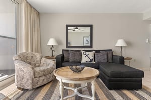 Stylish living room with coastalthemed decor, comfortable seating, and natural light streaming through floortoceiling windows.