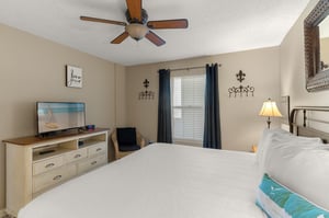 Rest easy in Bedroom 1 styled with coastal touches, a ceiling fan for comfort, and entertainment at your fingertips.