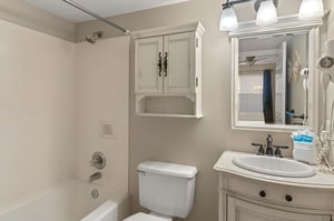 Bathroom 1 features a relaxing tub, modern vanity with mirror, and thoughtful storage to keep your essentials organized during your stay.