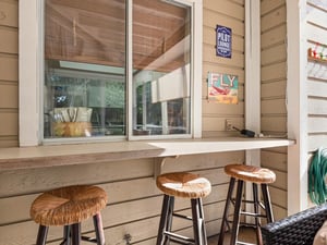 Grab your morning coffee at this charming outdoor bar setup, where vintage aviation signs and woven stools create the perfect spot to start your day.