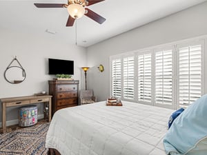 Unwind in your serene bedroom where coastal breezes flow through plantation shutters and a ceiling fan keeps you cool.