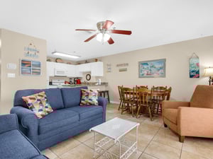 Your bright openplan living space features a comfy blue sofa, dining table for six, and fully equipped kitchen—perfect for gathering with family.