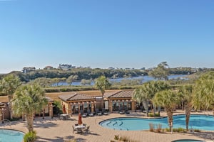 Spacious pool area featuring multiple swimming pools, hot tubs, and lush tropical landscaping with coastal views beyond.