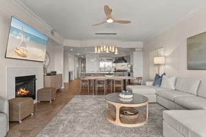 Unwind in your elegant living space where modern comfort meets coastal charm, complete with a crackling fireplace and open kitchen.