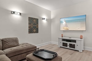 Sink into plush seating and enjoy your favorite movies or shows on the large TV, with coastal artwork creating a serene atmosphere.