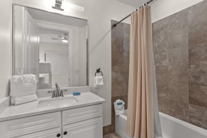 Unwind in your elegant bathroom featuring tile walls, crisp white vanity, and plush towels awaiting your arrival.