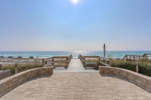 Stonepaved pathway leads through dunes to pristine white sand beach.