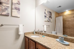 Spacious ensuite bathroom features granite countertops, warm wood cabinetry, and a relaxing shower where you can unwind after pool days.