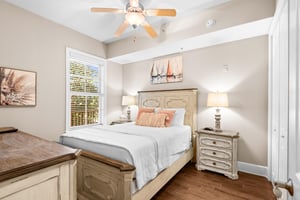 Recharge in this queen bedroom with warm coastal décor, gentle ceiling fan breeze, and coastal artwork.