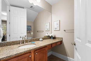 Half bathroom located just off the kitchen area, with granite countertops and warm wood cabinetry.