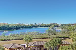 Coastal community nestled among native vegetation along pristine gulf and lake waters under clear blue skies.