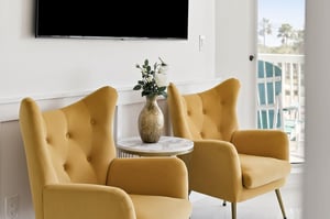 Unwind in stylish yellow wingback chairs with your favorite show playing on the mounted TV, while palm trees sway outside your window.