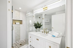 Step into your spalike bathroom featuring gleaming white marble, gold accents, and a stunning mosaictiled walkin shower.
