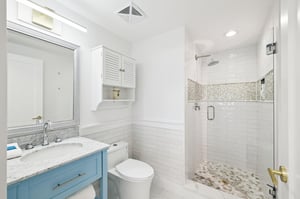 Refresh in your spainspired bathroom with marble counters, rainfall shower, and coastalchic blue vanity.