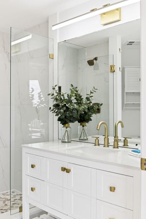 Pamper yourself in this elegant marble bathroom with brass fixtures, fresh eucalyptus, and a luxurious glassenclosed shower.