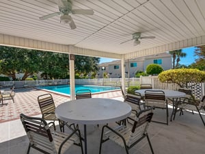 The covered patio offers cool shade and poolside dining with ceiling fans