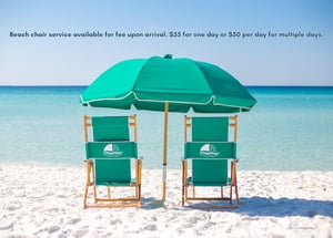 Two beach chairs and umbrella set up on pristine white sand facing turquoise waters.