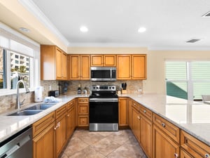 The fullyequipped kitchen invites culinary adventures with warm wood cabinets, granite counters, and modern appliances for memorable meals.