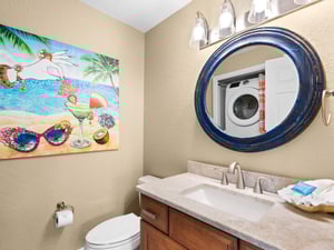 Bathroom 3  The coastalthemed bathroom features a tropical mural, elegant round mirror, and convenient washerdryer for your beach day essentials.