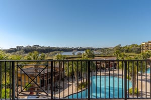 Wake up to stunning views just off the king primary bedroom, where sparkling pool waters and tropical palms frame Gulf and Lake views