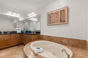 Luxurious primary bathroom features a spacious jetted tub, elegant travertine surroundings, and premium fixtures for your ultimate relaxation.