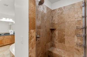 Step into this luxurious shower featuring a rainfall head and builtin bench.