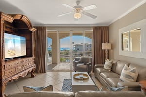 Unwind in the elegant living space with leather seating, entertainment center, and stunning balcony views of the coastline beyond.