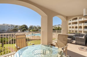 Spacious covered balcony with pool views and comfortable seating for dining and lounging.