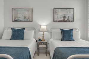 Relax in your coastalthemed double bedroom, featuring crisp white linens and soothing blue accents that mirror the serene artwork above.
