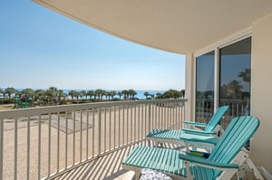 Unwind on your private balcony with stunning ocean views, where turquoise chairs invite you to relax while palm trees sway in the coastal breeze.
