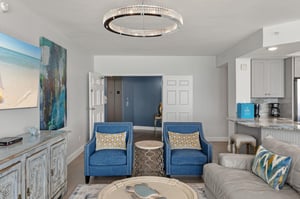 Relax in your sophisticated living space with coastal artwork and stunning chandelier creating perfect ambiance.