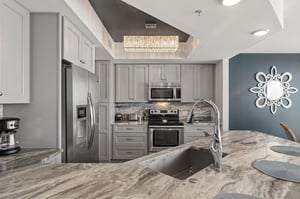 Your fully equipped kitchen features elegant gray cabinetry, marble countertops, and modern stainless appliances for homecooked meals.