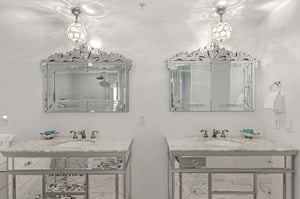 Your luxurious bathroom features dual vanities with Venetian mirrors and sparkling pendant lights, creating an elegant space for your morning routine.