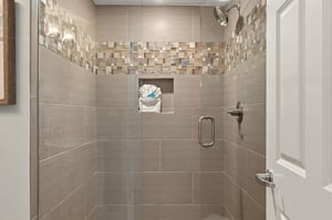 Step into your elegant tiled shower with beautiful mosaic accents and a convenient builtin niche for your toiletries.